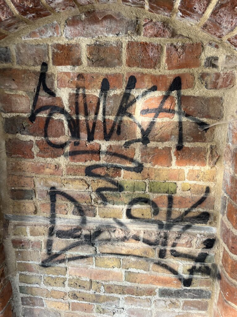 Graffiti entfernen 12 Vorher-Bild einer Graffitireinigung: Vollständige Beseitigung von Sprühfarbe auf Backstein im Denkmalschutz durch mobile Lasereinheit